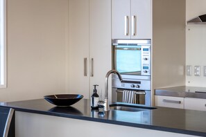 Microwave, stovetop, dishwasher - The Penthouse On The Beach at The Sands (11) - The Penthouse On The Beach is a bright, elevated apartment above Onetangi Beach with wide sea views across the bay. Open plan living flows to a large north-facing deck set up for outdoor dining and relax (Waiheke Island)