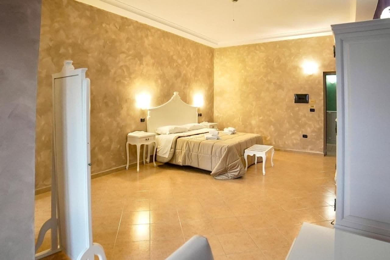 A hotel room with a large bed, bedside tables, a mirror, and a wardrobe.