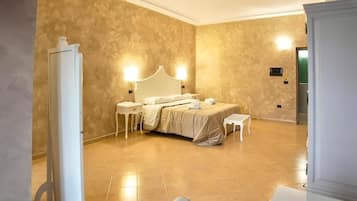 A hotel room with a large bed, bedside tables, a mirror, and a wardrobe.