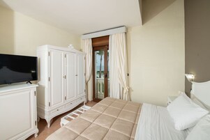 Un dormitorio con cama, armario, televisor y vistas al exterior a través de una puerta.