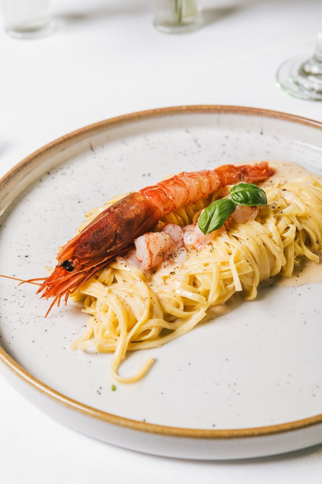 Een bord pasta met garnalen en basilicum.