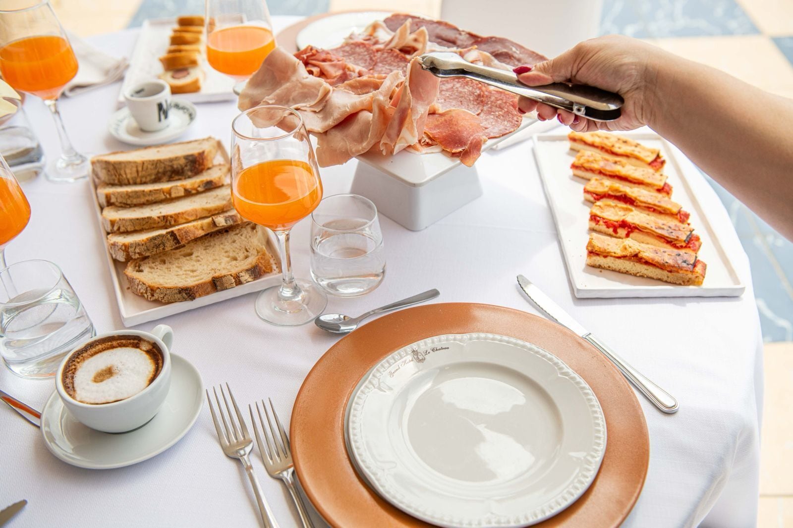 Una colazione con pane tostato, succo d'arancia, caffè e un piatto di salumi.