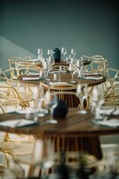 Una mesa de comedor redonda con varias sillas, cada una con respaldo dorado.