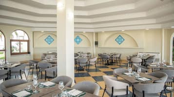 A restaurant with multiple tables and chairs, arranged in a spacious layout with a checkered floor pattern.