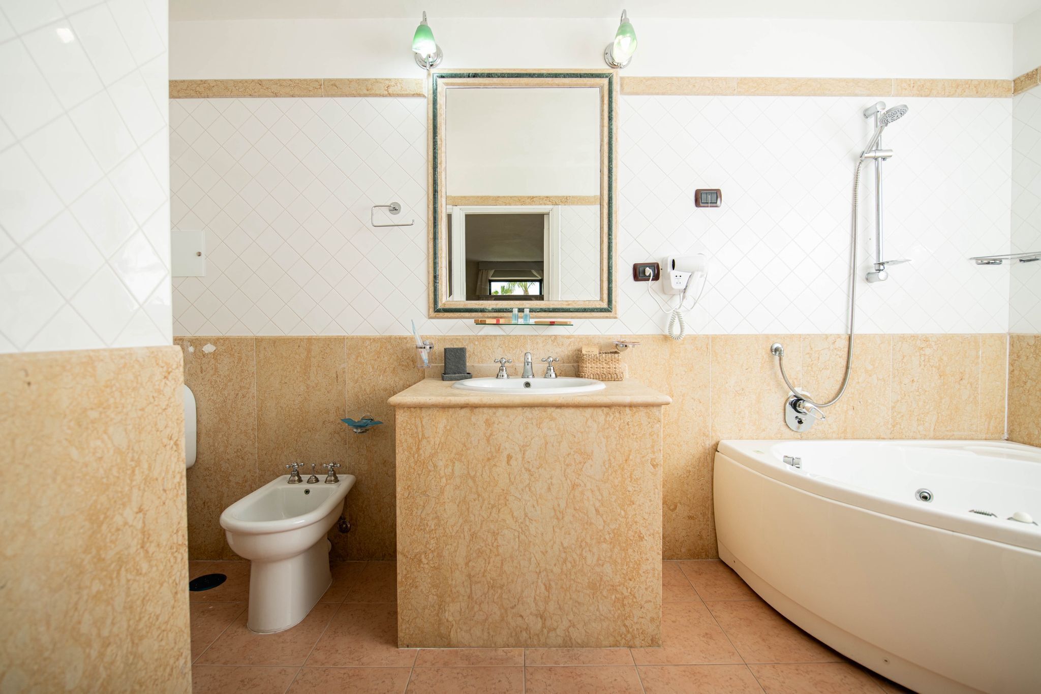 Een badkamer met een toiletbidet, wastafel, spiegel en bad.