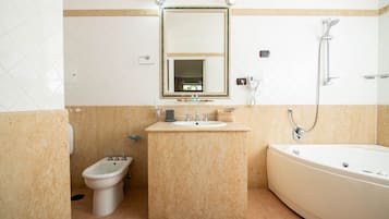 A bathroom with a bidet, sink, mirror, and bathtub.