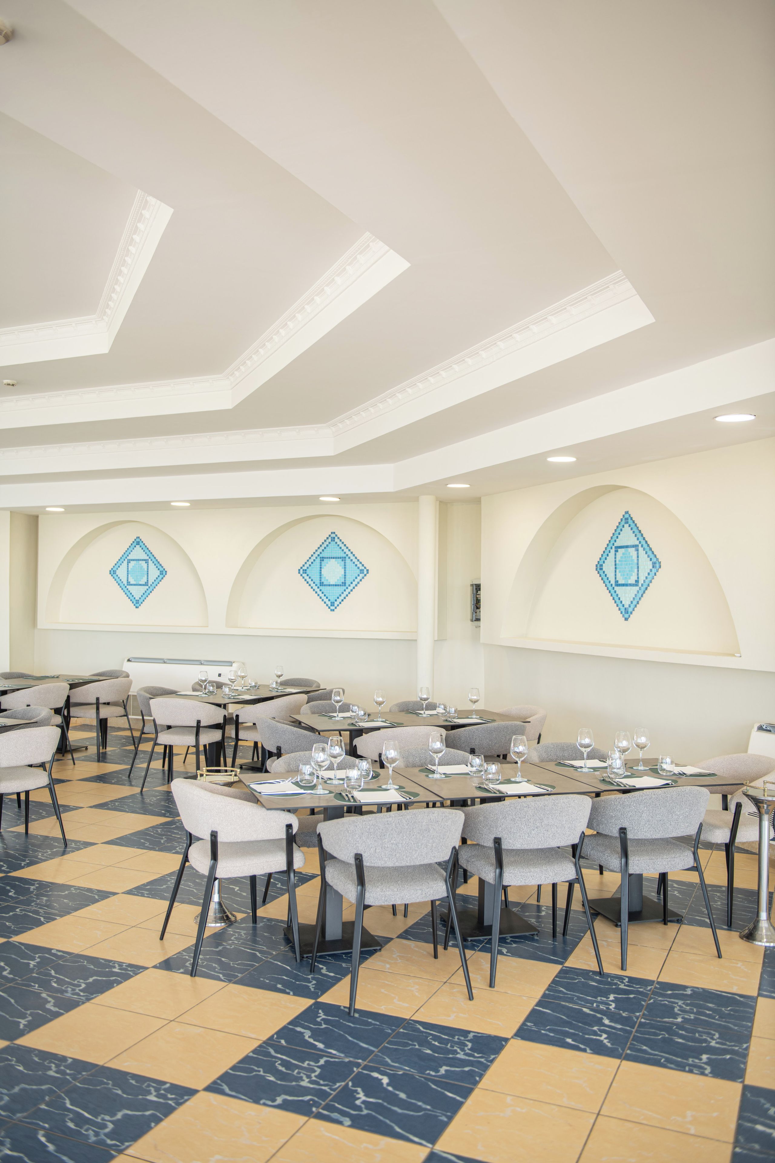 A conference room with tables and chairs, a patterned floor, and decorative wall elements.