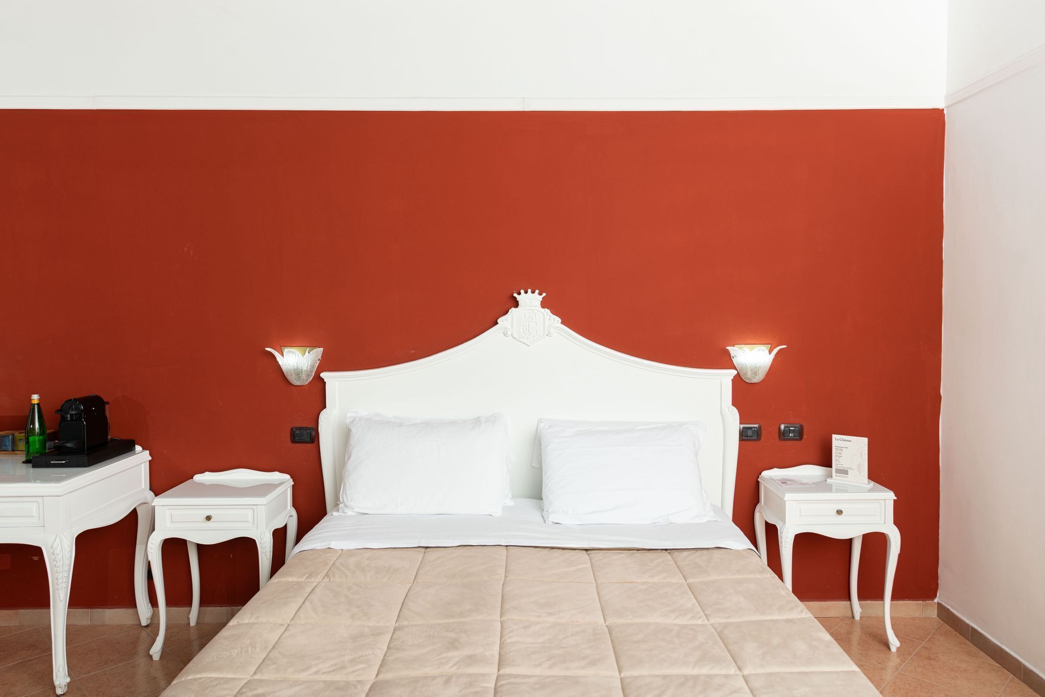 Ein ordentlich eingerichtetes Hotelzimmer mit einem großen Bett, zwei Nachttischen und einer roten Akzentwand.
