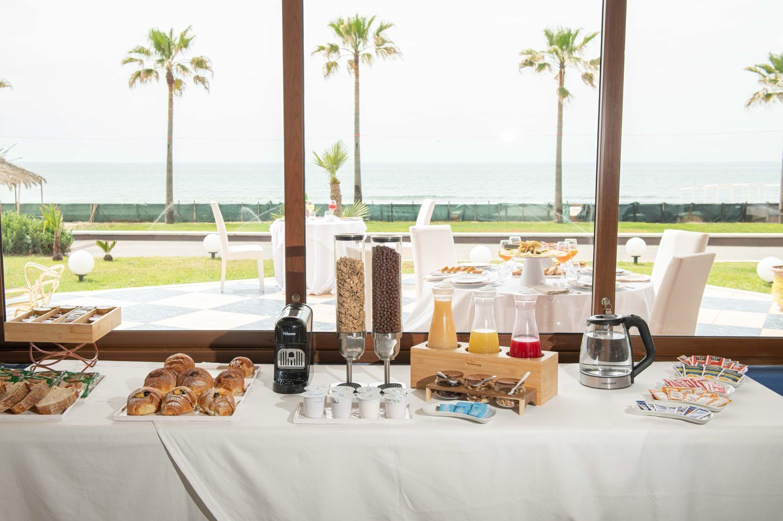 A breakfast buffet with pastries, beverages, and condiments.