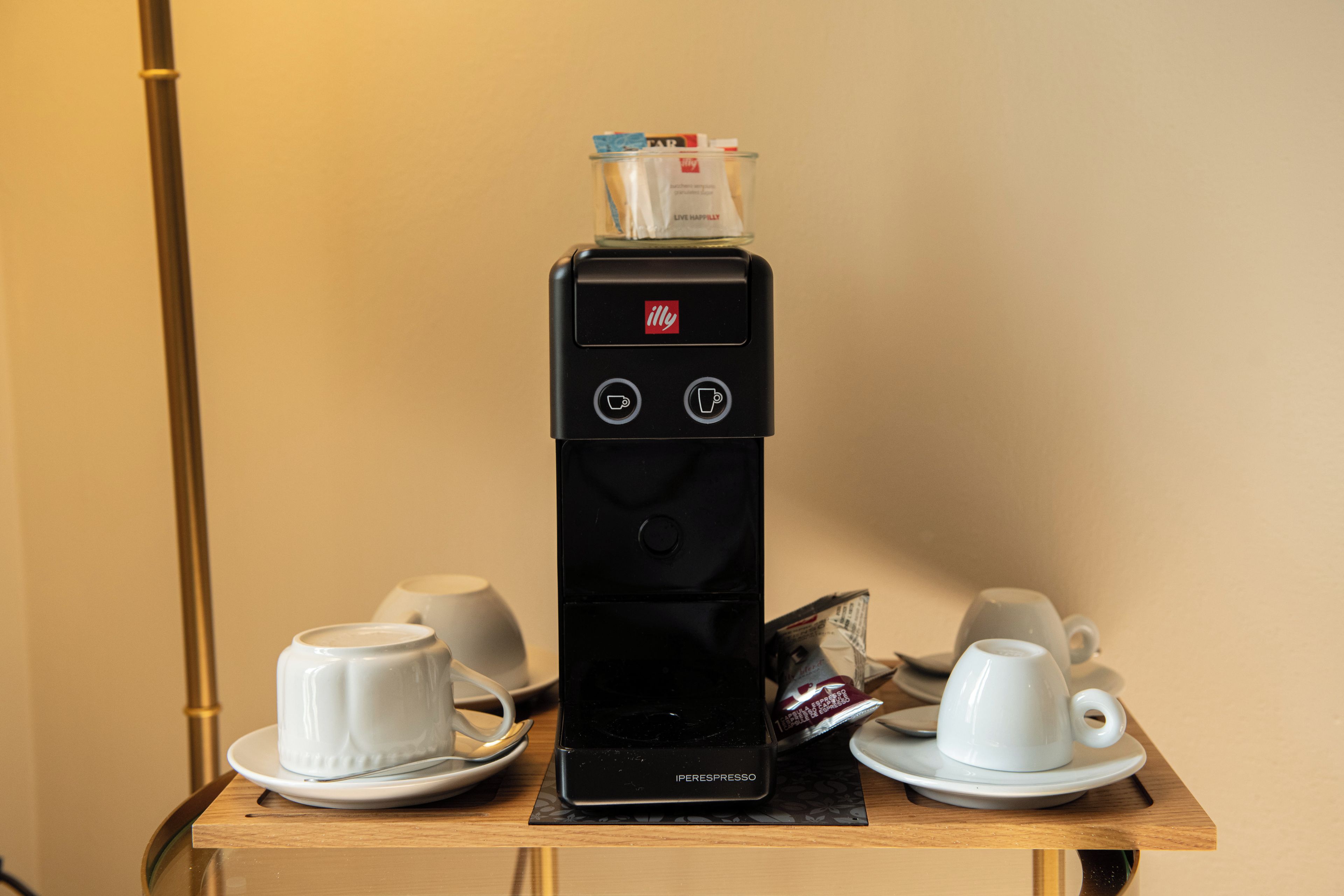 A coffee machine with two cups and a saucer on a table.
