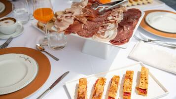 A table set with plates, cutlery, and a variety of meats and pastries.