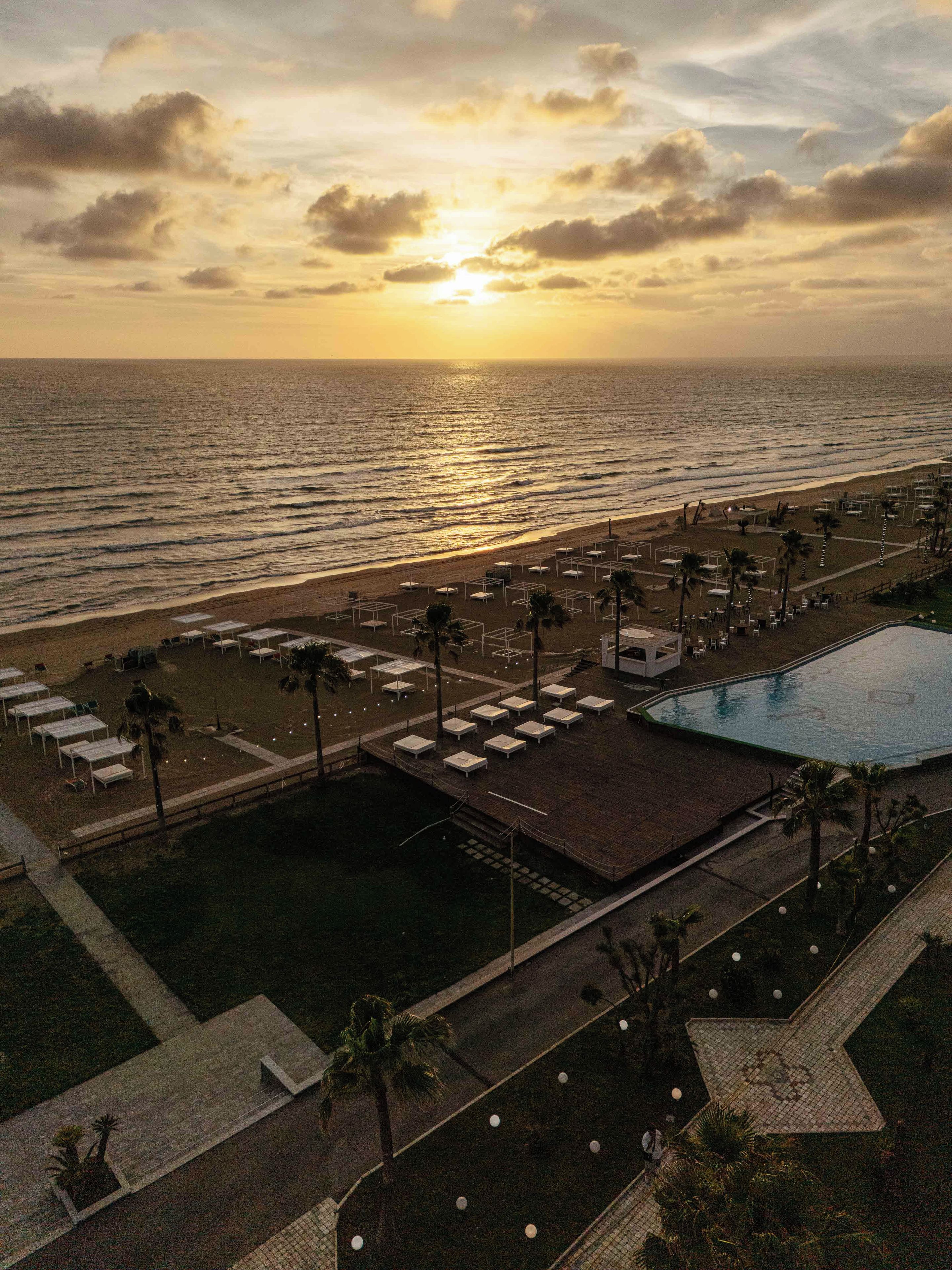 A resort with a pool, beach area, and lounge chairs.