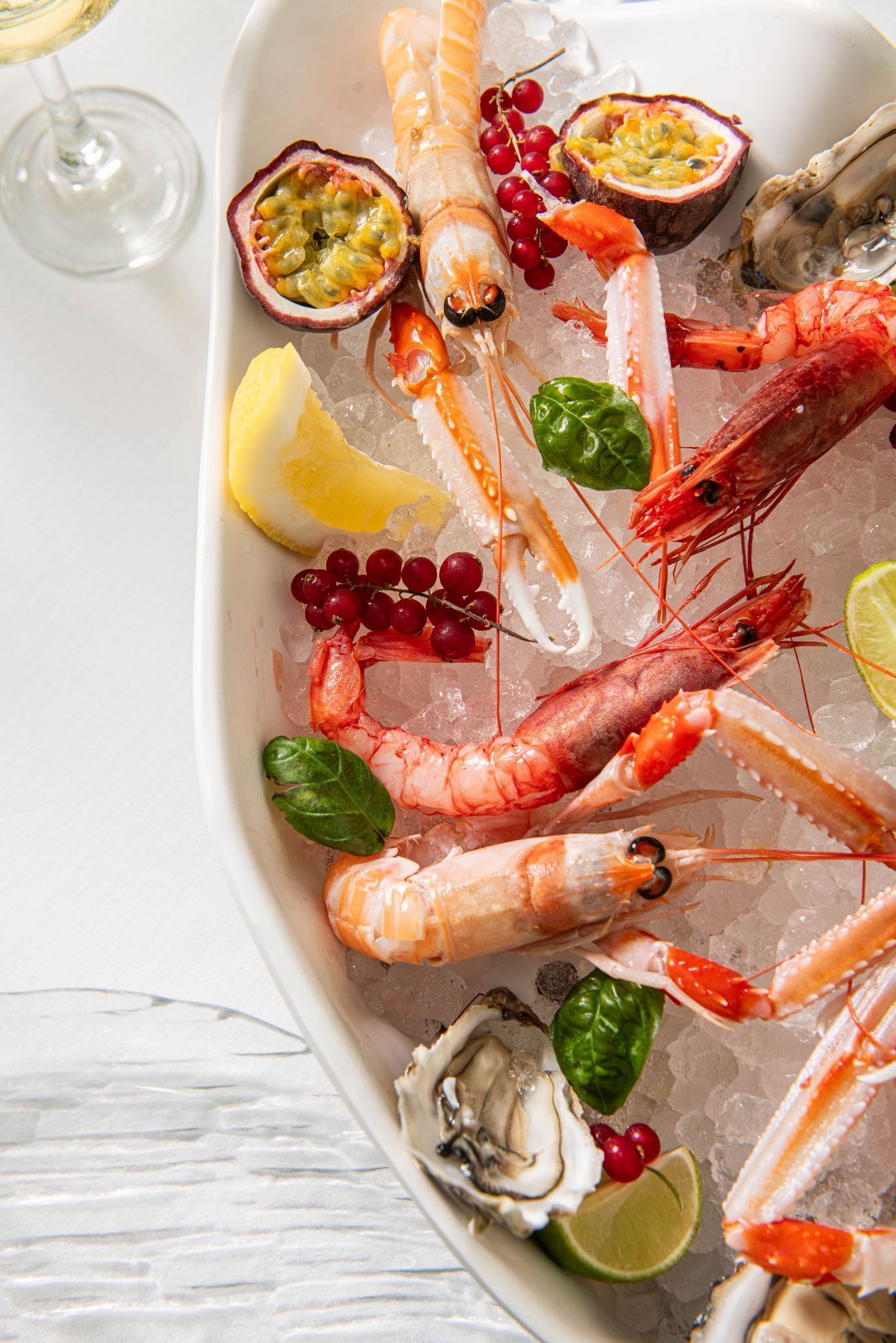 A seafood platter with shrimp, oysters, and citrus fruits on ice.