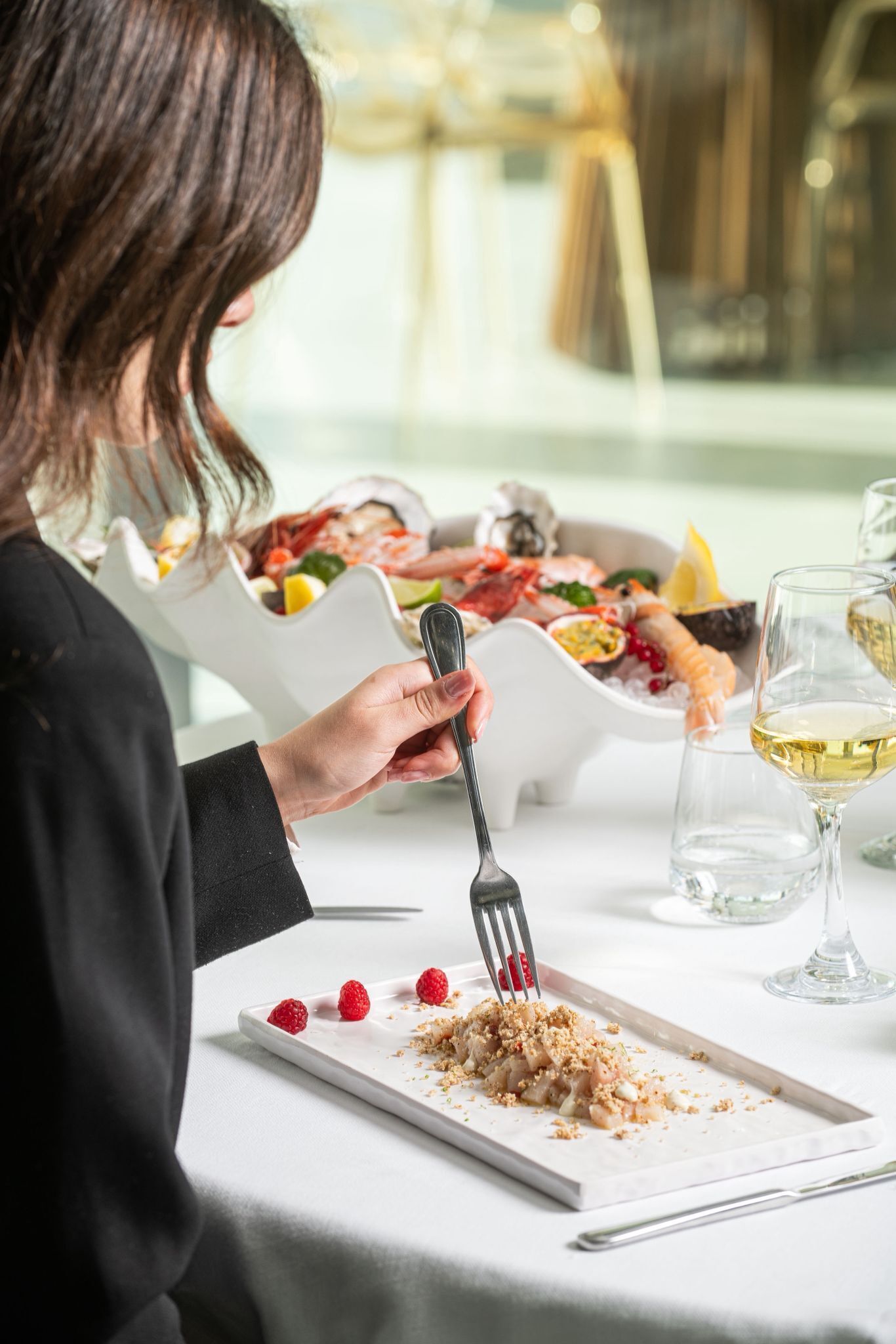 A dining table with a plate of food, a glass of wine, and a fork.