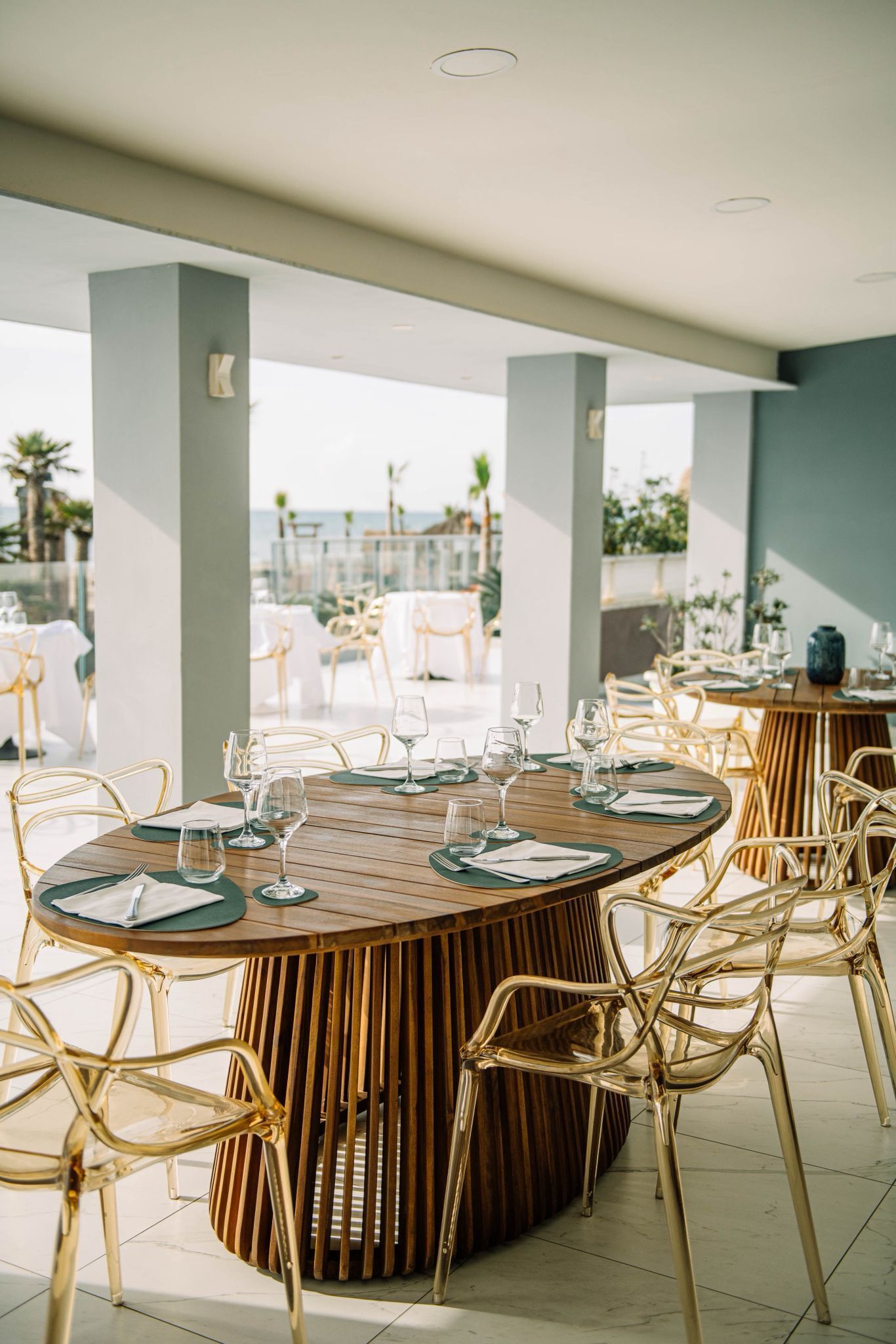 Un espace de restauration en plein air avec des tables rondes, des chaises et une vue sur la mer.