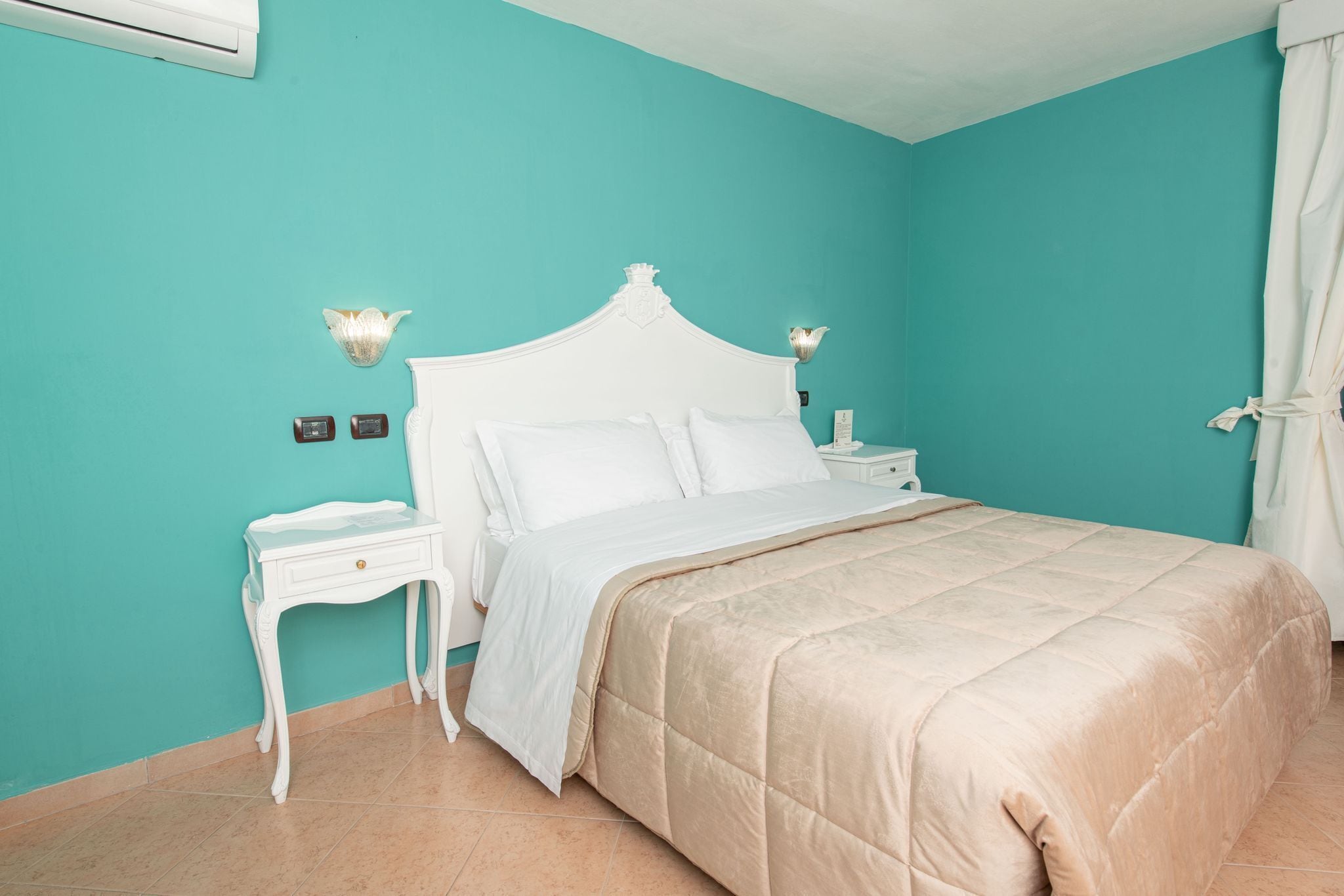A bedroom with a bed, nightstand, and wall-mounted lamp.