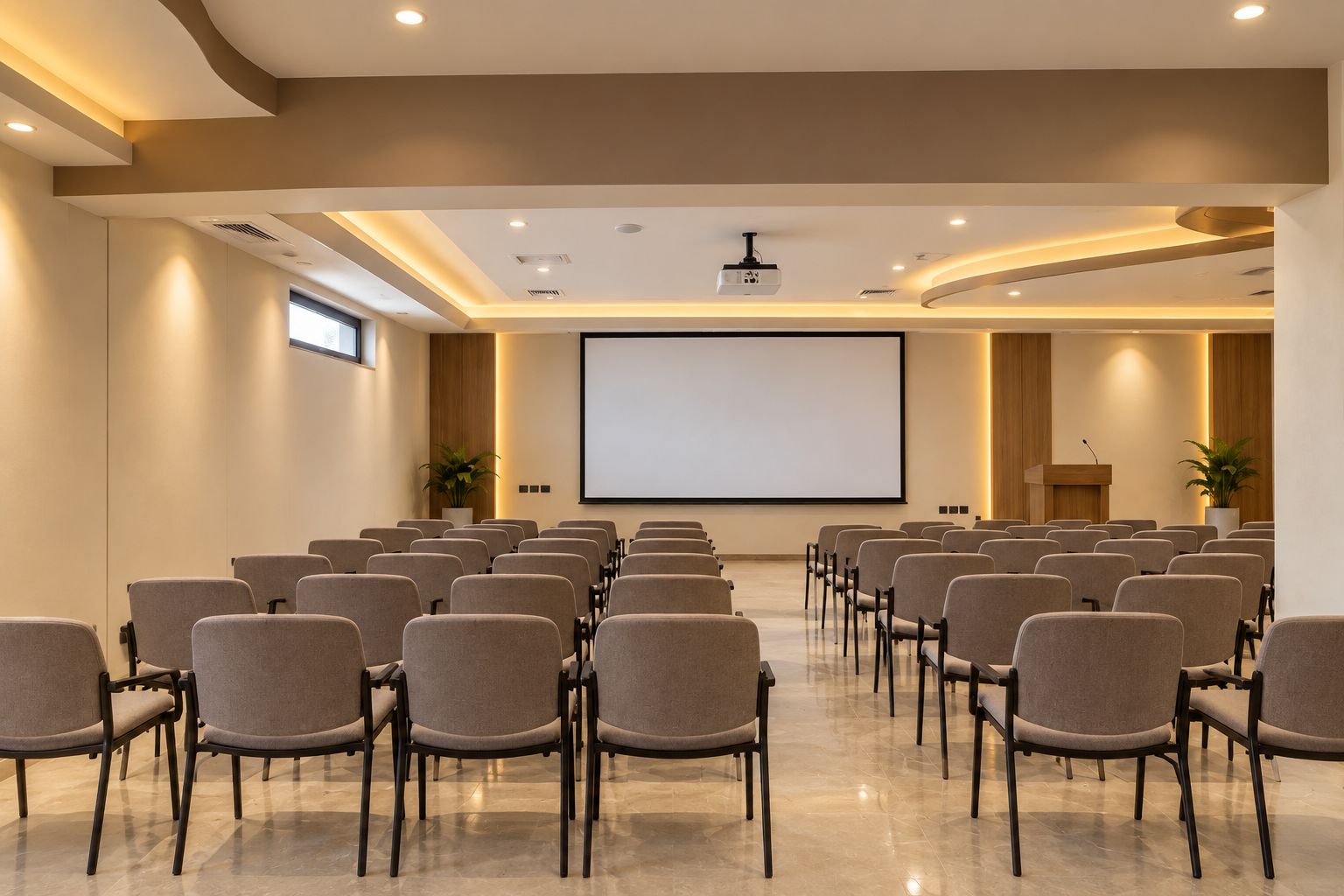 A conference room with rows of chairs, a large screen, and a podium.