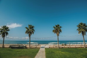 Un camino bordeando la playa que lleva a un quiosco blanco con vista al mar.