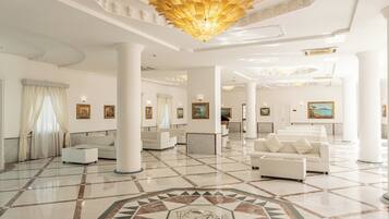 A spacious lobby with white columns, a patterned floor, and a large chandelier.