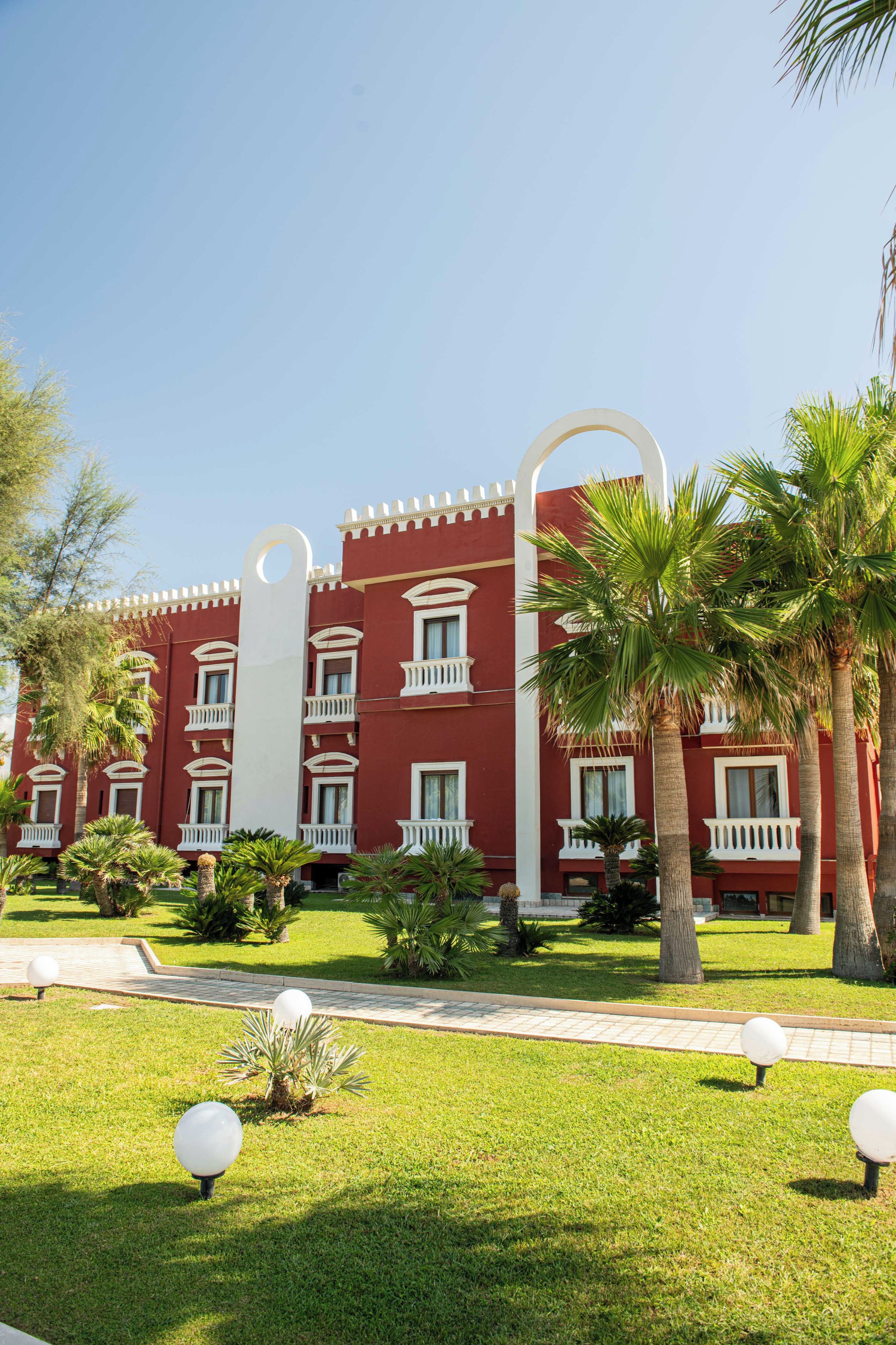A red building with white balconies and a clear sky.