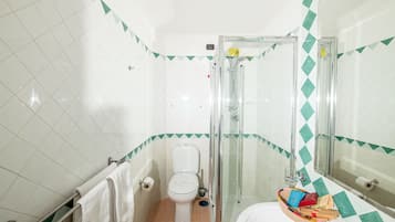 A bathroom with a toilet, shower, and sink.