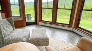 Habitación de esquina con un ventanal grande, una puerta y vistas a un paisaje verde.
