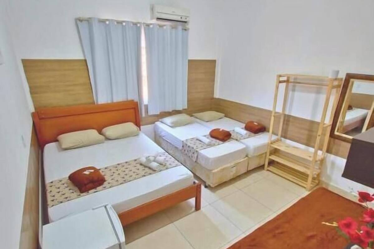 A room with two beds, a wooden headboard, a small table, and a mirror.