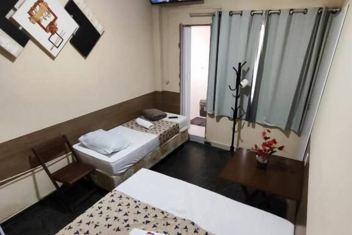 A hotel room with a bed, a desk, a television, and a window with curtains.