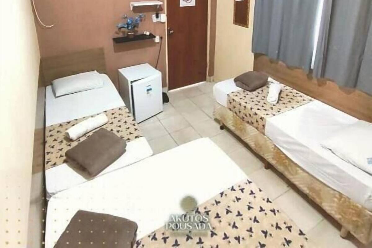A hotel room with two beds, a desk, a television, and an air conditioning unit.