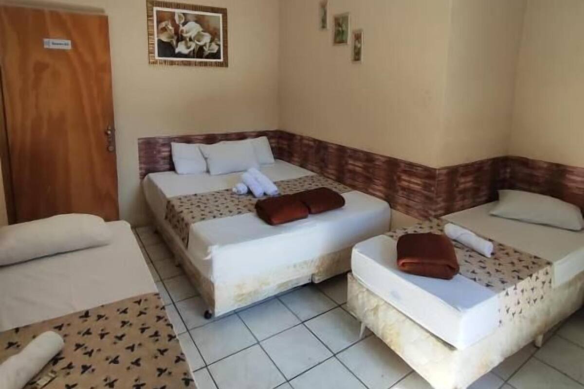 A hotel room with two beds, a ceiling fan, and a door.