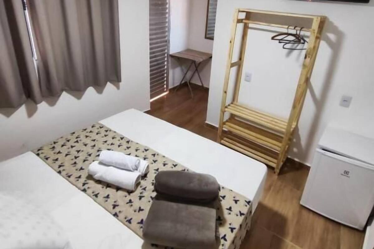 A hotel room with a bed, a desk, a television, and a wardrobe.