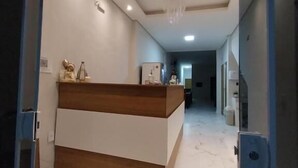 A modern reception area with a marble floor, a wooden reception desk, and recessed lighting.