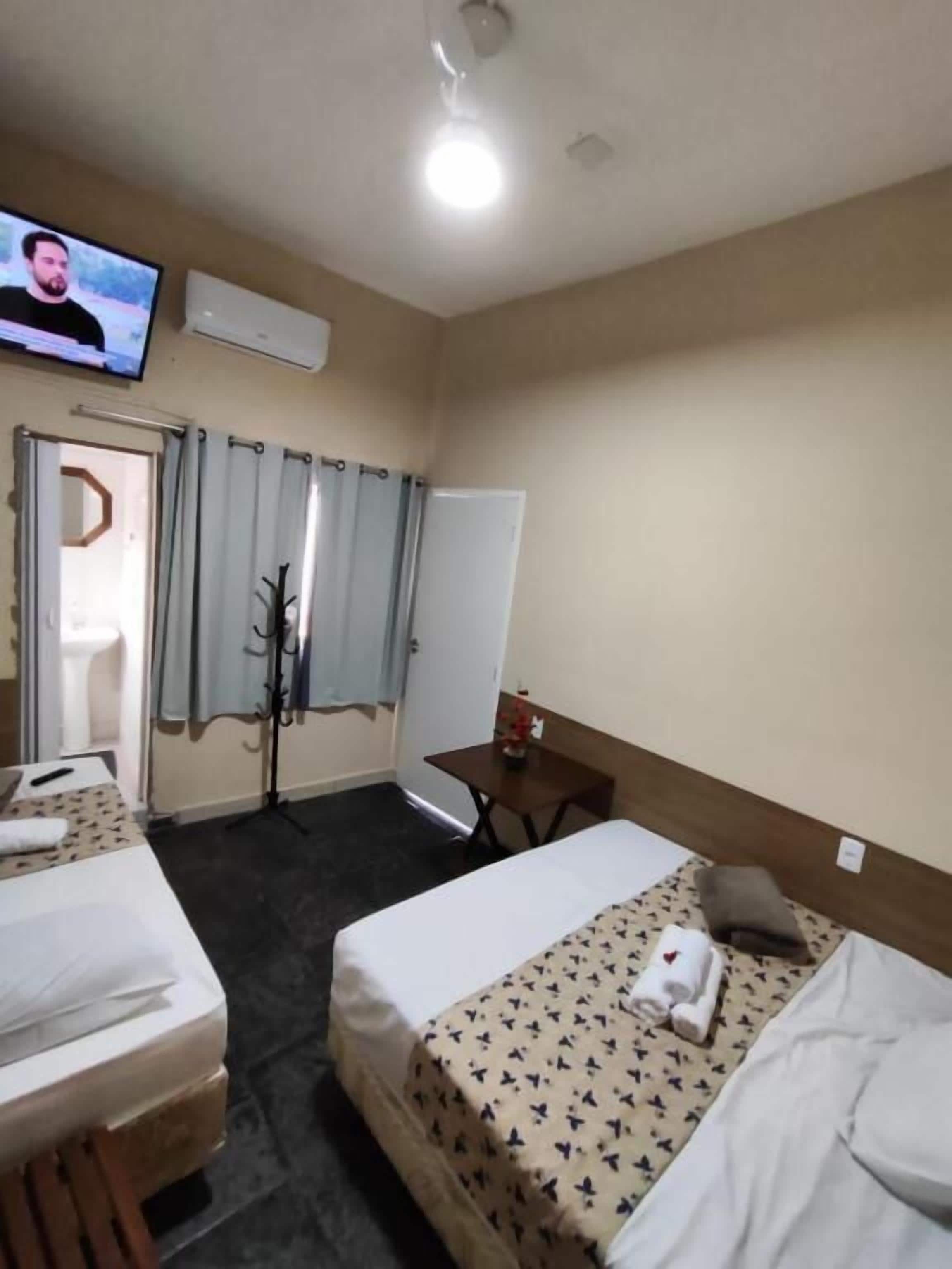 Habitación de hotel con dos camas, televisión, escritorio y espejo.