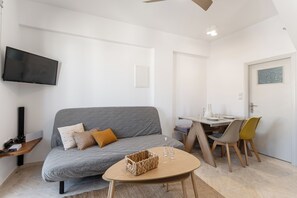 Ein modernes Wohnzimmer mit einem grauen Sofa, einem Holztisch und einem Essbereich mit Tisch und Stühlen.