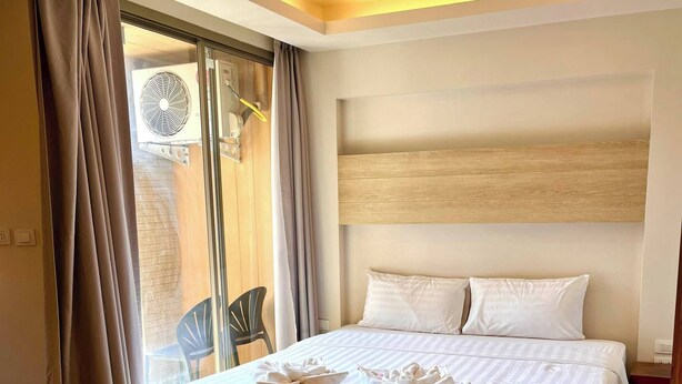 A hotel room with a large bed, wooden flooring, a ceiling fan, and a view through a sliding glass door. - Adventure Studio Aonang (Krabi)