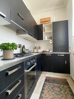 Eine moderne Küche mit dunklen Schränken, einem Gasherd, einer Spüle und einer kleinen Ablage für Küchenutensilien.