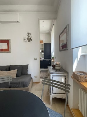 Ein gemütlicher Wohnbereich mit Sofa, Esstisch, einer kleinen Küche und einem Heizkörper.