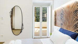 A bedroom with a bed, a mirror, a view through a sliding door, and a wall with a geometric pattern. - A' Malafemmena  (Positano)