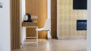 A modern room with a wooden wall, a TV mounted on the wall, a white chair, and a small table with a coffee maker and glasses. - A' Malafemmena  (Positano)