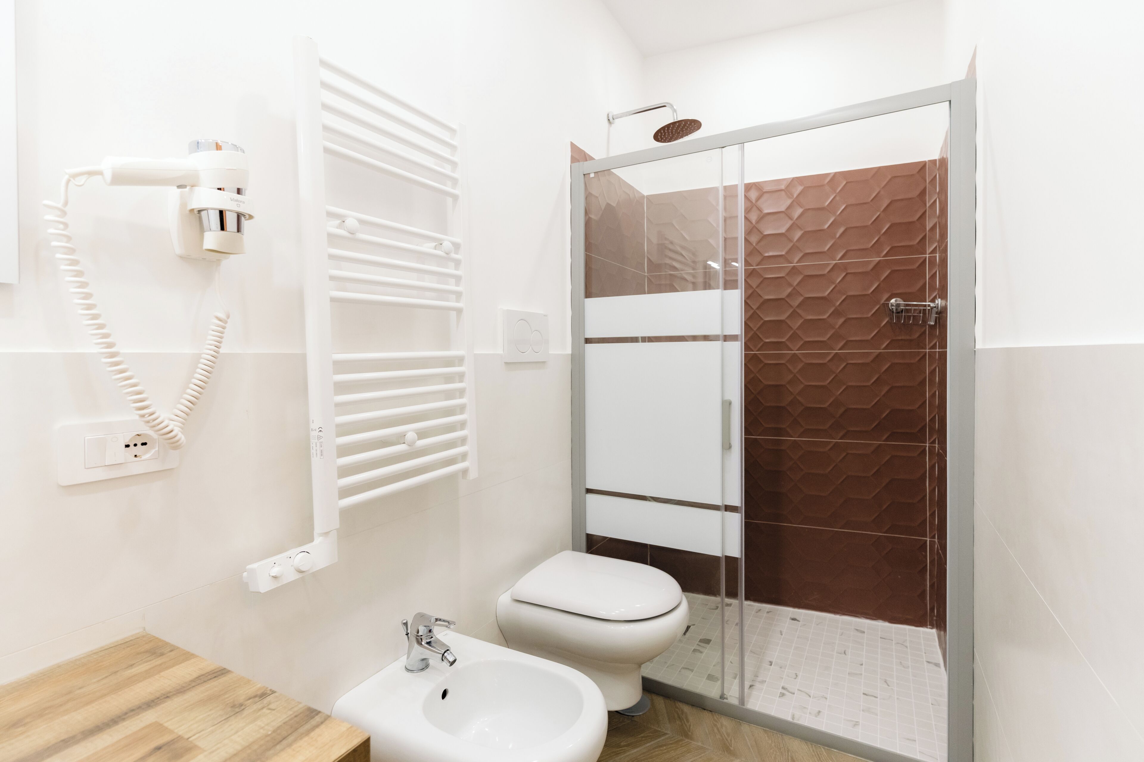 A bathroom with a toilet, bidet, and a glass-enclosed shower.
