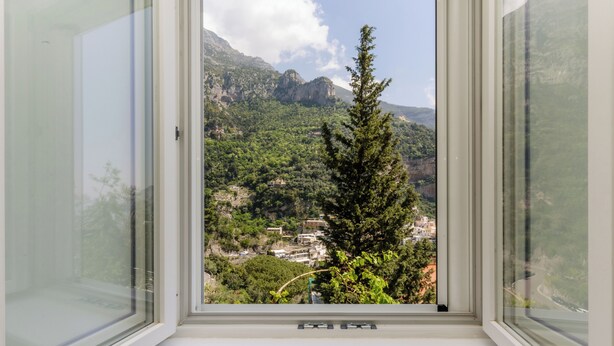 A window with a view of a mountainous landscape, a tree, and a road. - A' Malafemmena  (Positano)