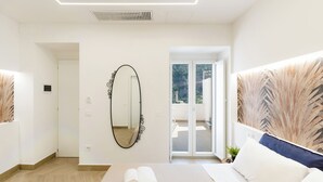 A hotel room with a bed, a mirror, a view through a glass door, and a plant on the windowsill. - A' Malafemmena  (Positano)