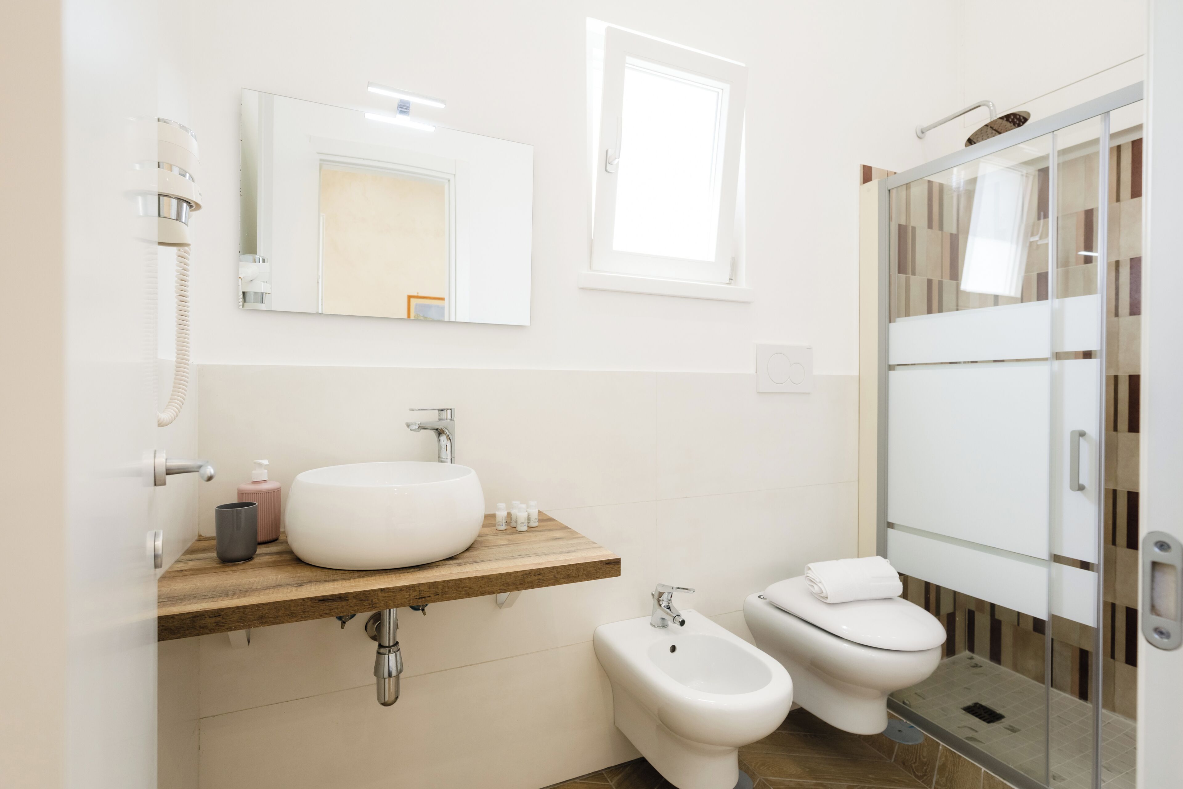 A modern bathroom with a large sink, bidet, toilet, and a glass shower enclosure.