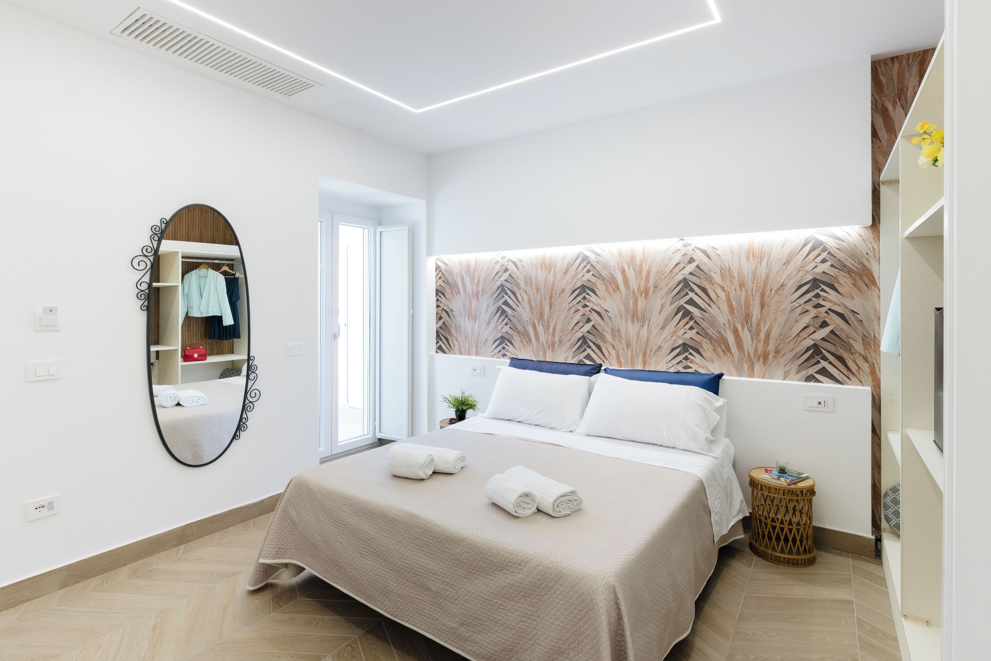 Un dormitorio ordenado con cama, espejo y armario.