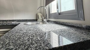 Une cuisine dotée de plans de travail en granit, d’un évier en acier inoxydable, d’une bouilloire et d’une fenêtre offrant une vue agréable.