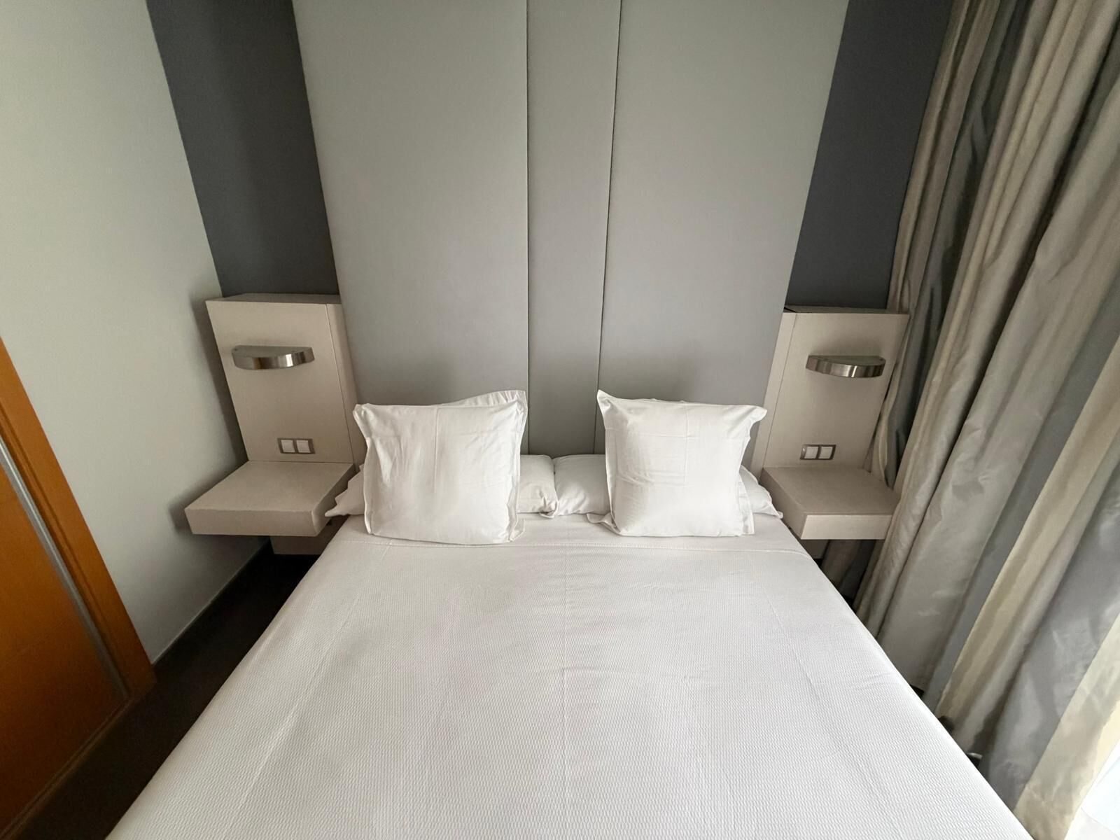 A hotel room with a large bed, two bedside tables, and a headboard.