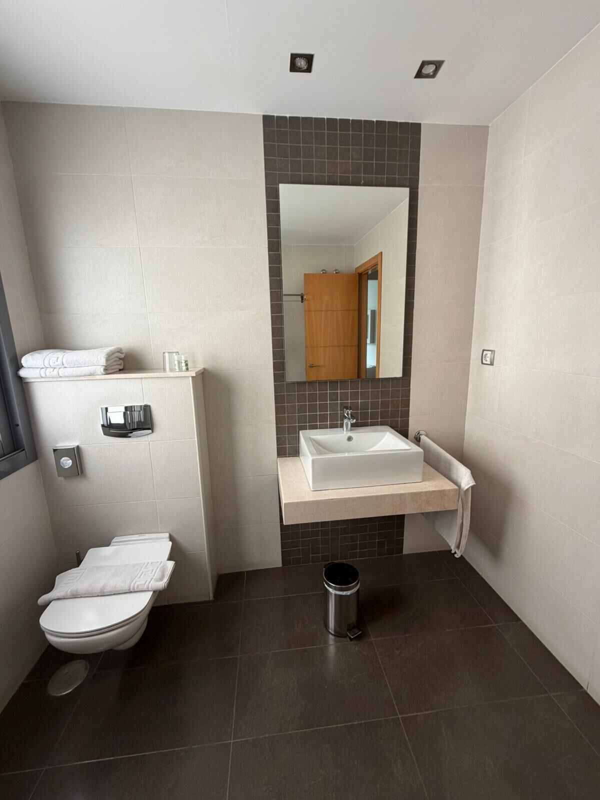 A modern bathroom with a toilet, sink, and mirror.