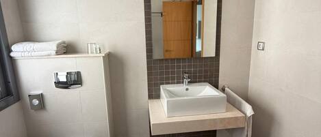 A modern bathroom with a toilet, sink, and mirror.