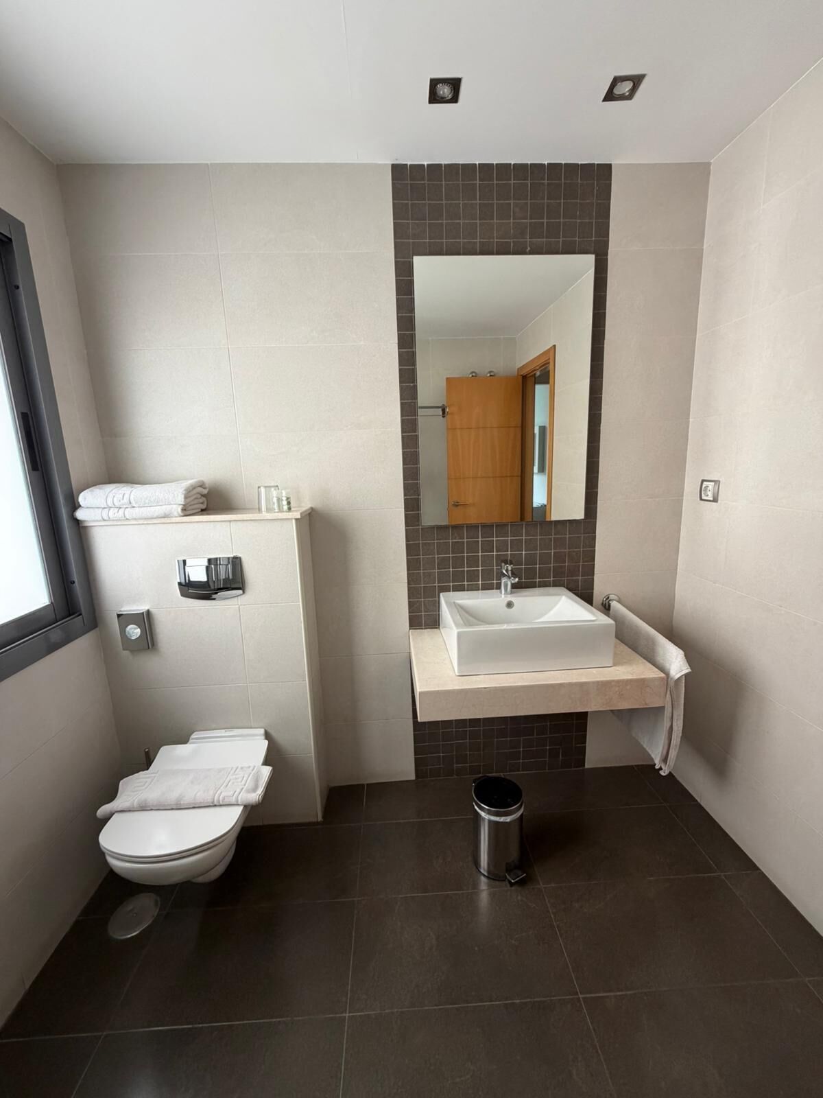 A modern bathroom with a toilet, sink, and mirror.
