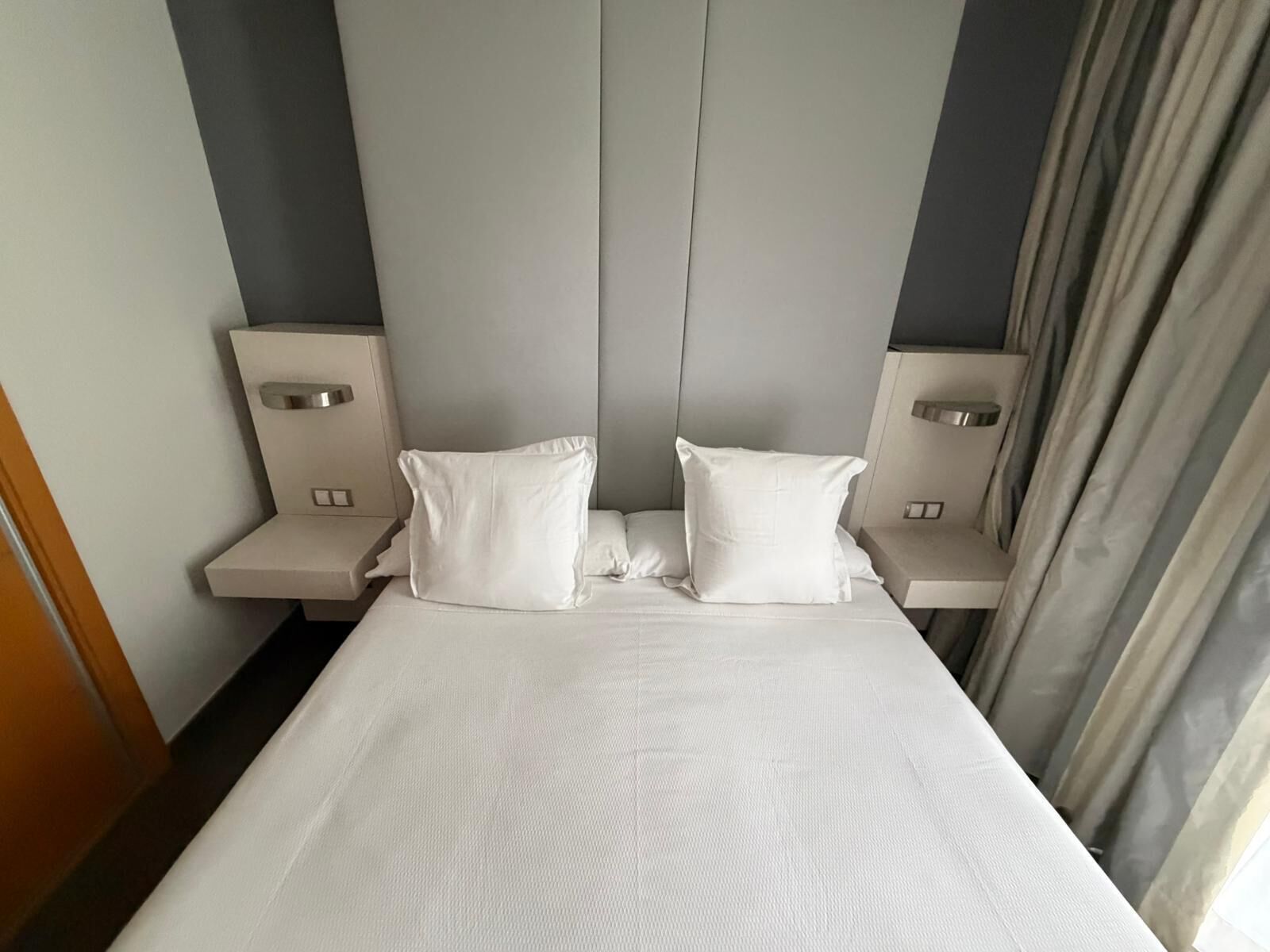 A hotel room with a large bed, two bedside tables, and a headboard.